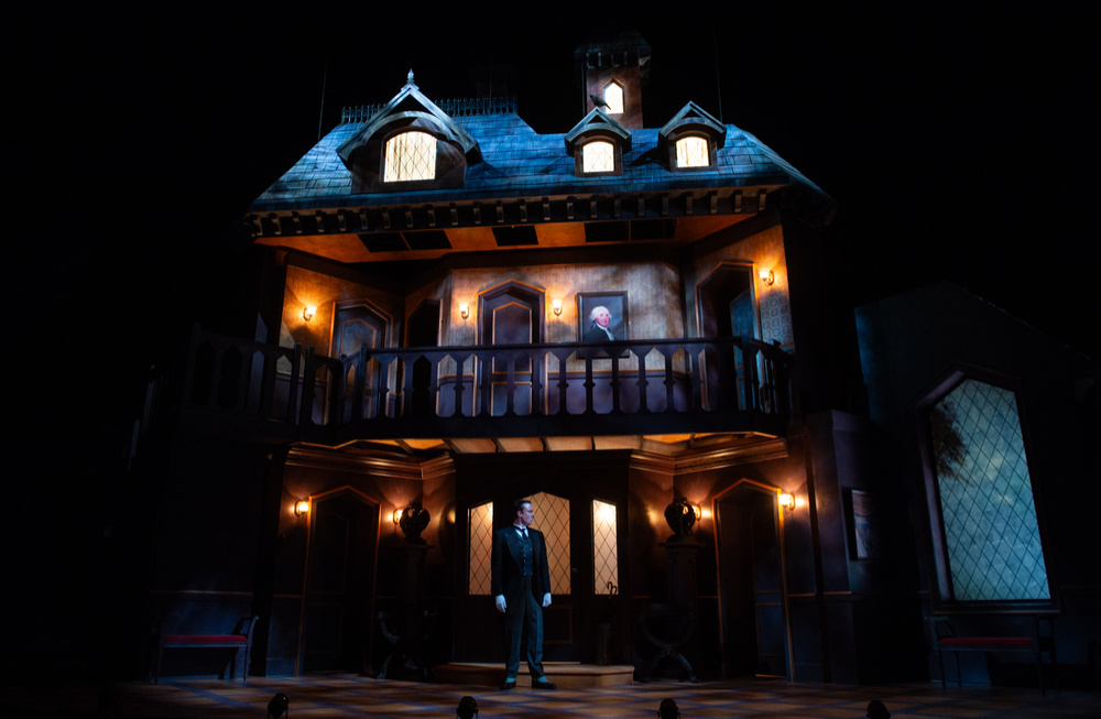 A dark, foreboding mansion with a butler in the foreground.