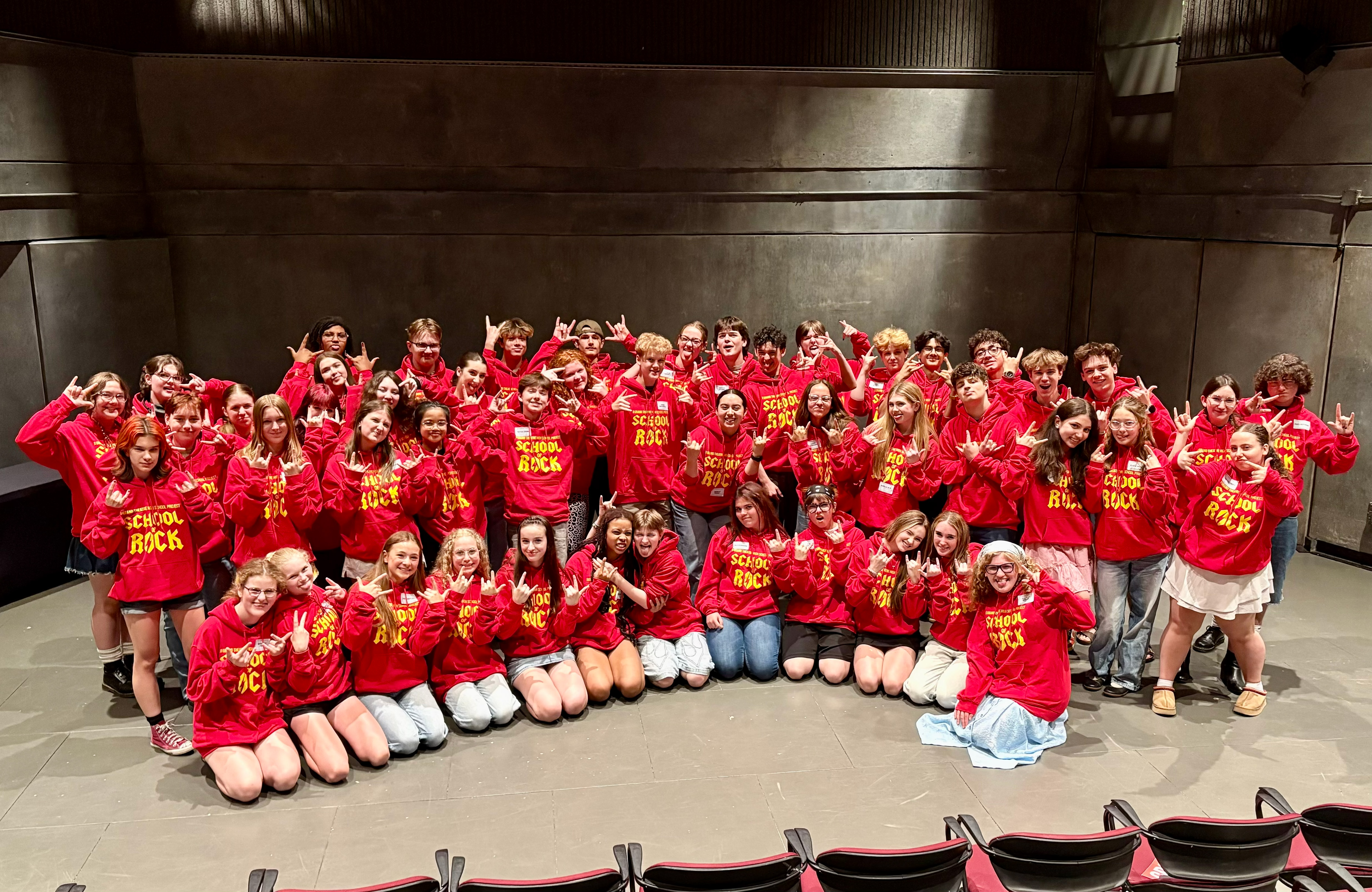 Student company takes a group photo on the Auburn Stage in their High School Project hoodies.