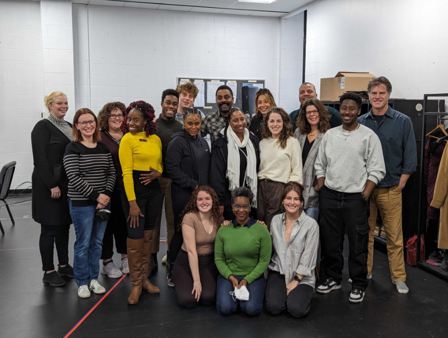 The cast and creative team of Controlled Damage pose for a photo in the rehearsal hall.