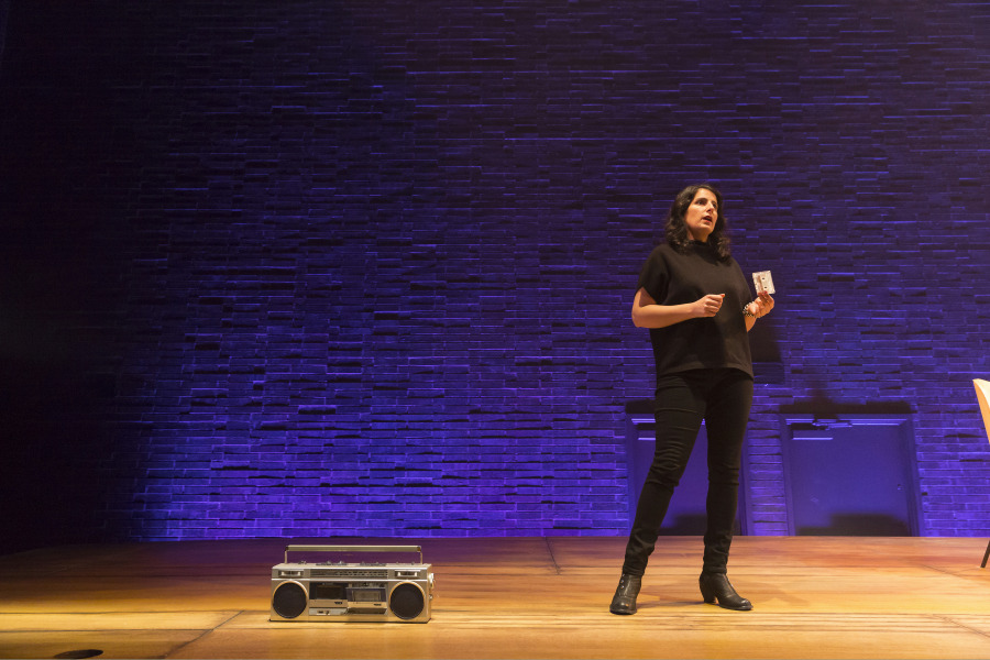 Zorana Sadiq holds a cassette during a performance of MixTape, a boombox sits on the stage nearby.
