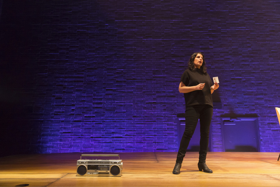 Zorana Sadiq holds a cassette during a performance of MixTape, a boombox sits on the stage nearby.