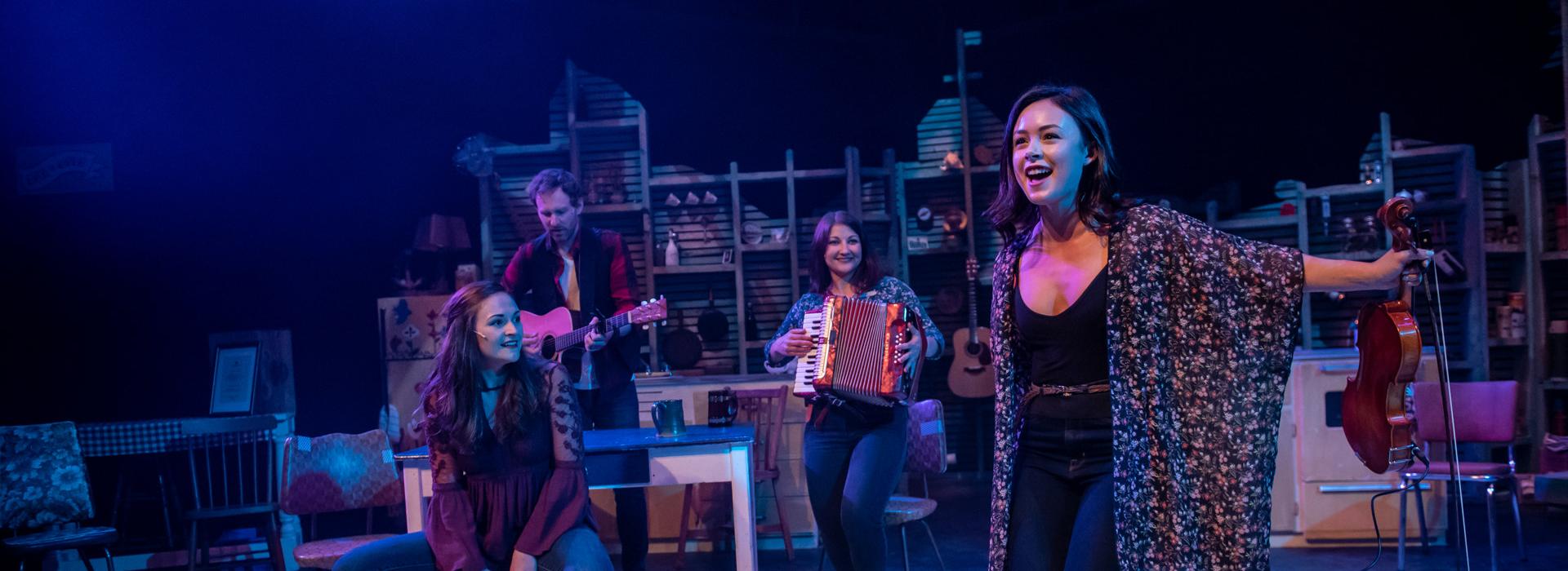 Photo by Stoo Metz, and features Malia Rogers, Celia Owen, Karen Lizotte, and Ian Sherwood in a performance of East Coast Kitchen Party.